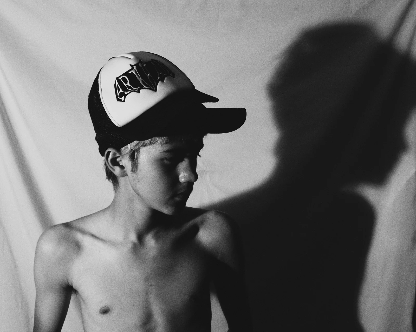 black-and-white self-portrait with a fabric backdrop